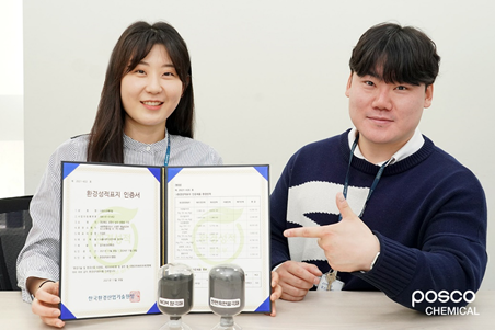 변혜란 대리와 최기승 사원이 취득한 환경성적표시 인증서를 앞에 두고 기념사진을 남기는 모습