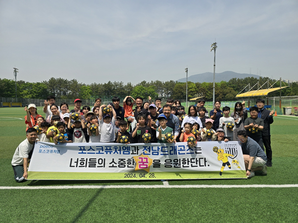 포스코퓨처엠 광양양극소재실 임직원들과 전남드래곤즈 선수들이 28일 금호동 송죽구장에서 세풍&middot;여천지역 어린이를 위한 축구 클리닉을 실시한 후 참가자 및 가족들과 함께 기념사진을 촬영하고 있다.