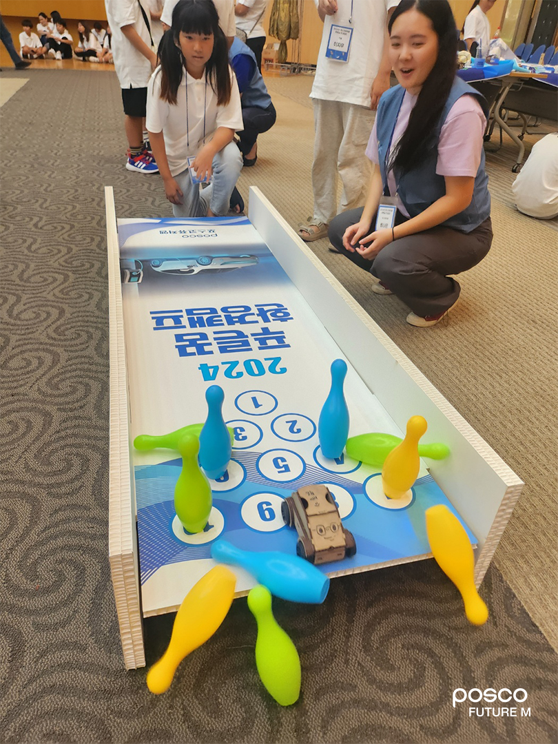 어린이들이 직접 만든 전기차로 볼링 게임을 하고 있다.