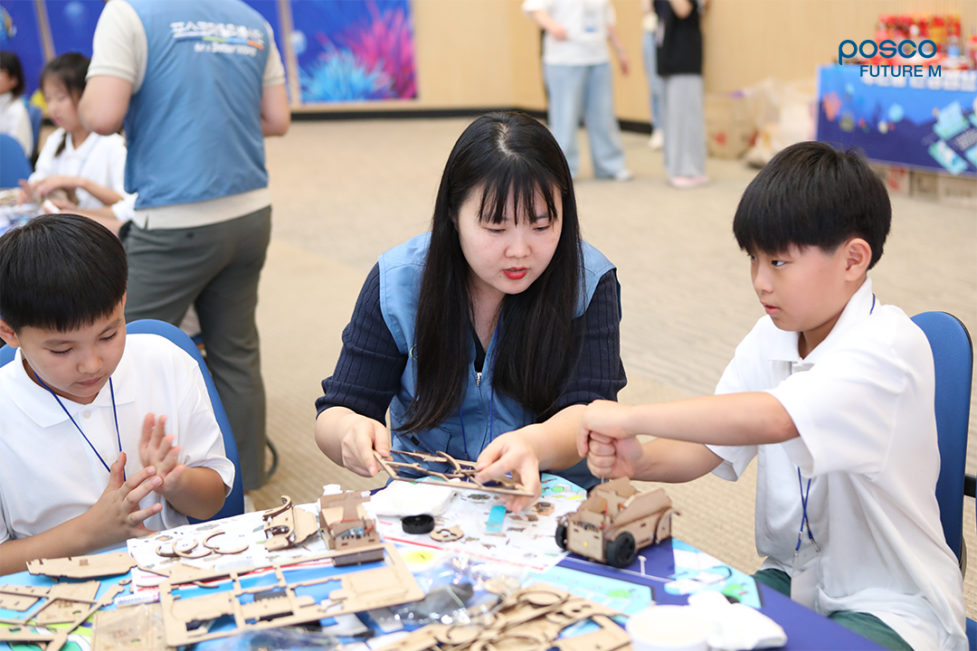 포스코퓨처엠 직원이 푸른꿈 환경캠프에 멘토로 나서 어린이와 함께 전기차 모형을 제작하고 있다