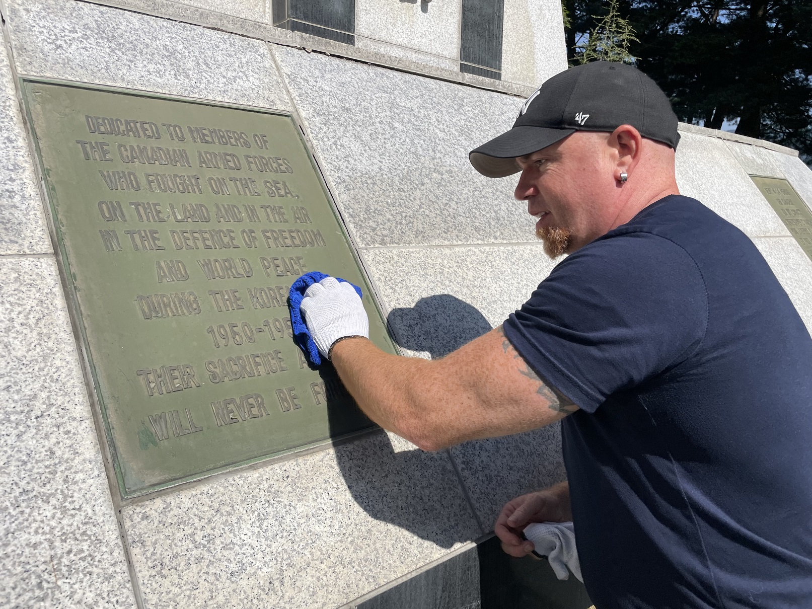 얼티엄캠 직원이 봉사활동을 하며 캐나다전투기념비를 닦고 있다.